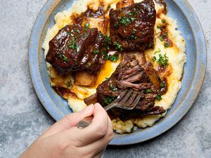 Short ribs served over mashed potatoes with a fork taking a piece