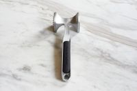 A mallet-style meat pounder on a marble surface