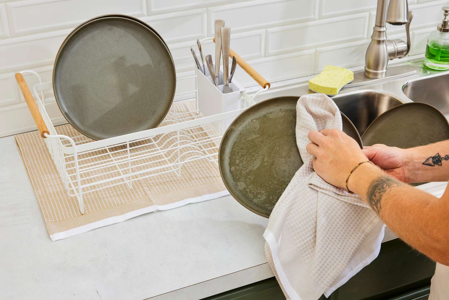 A person using a waffle weave dish towel to dry dishes.