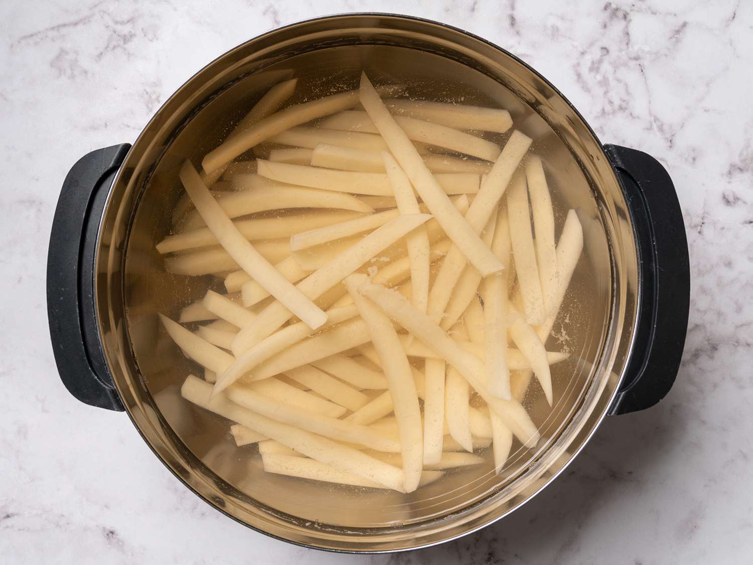 Fries soaking in a large bowl of water