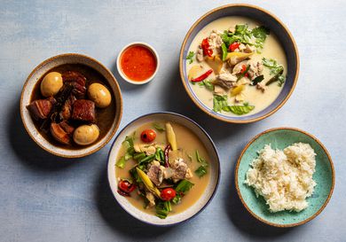 Overhead view of three Thai soups with rice and dipping sauce.