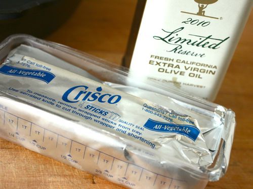 A bottle of extra-virgin olive oil and a stick of shortening, Crisco. 