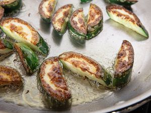 Pieces of cucumber browning in a frying pan