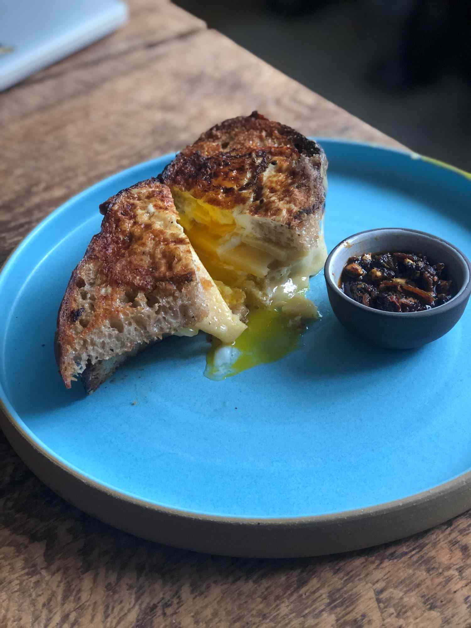 Grilled cheese explosion on a plate with a side dipper of chili crisp