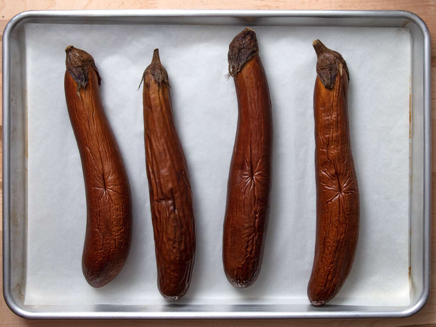 4 roasted eggplants on a baking sheet