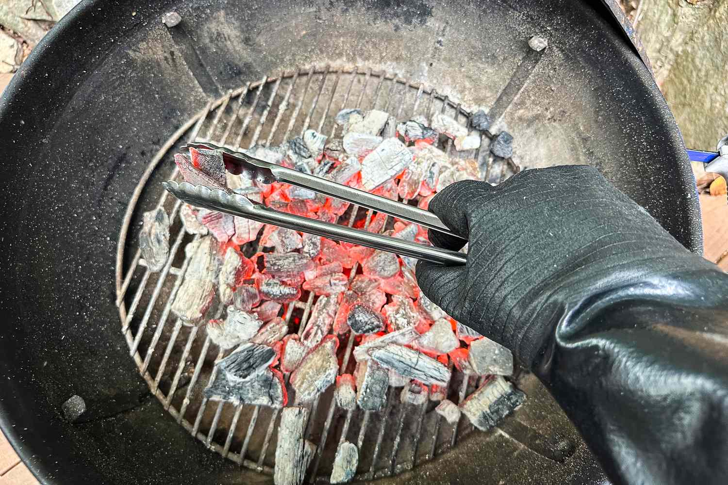 A person holds a pair of tongs while wearing the Grill Armor Gloves BBQ Waterproof Gloves