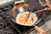 A person cooks rice and carrots in the Joyce Chen Carbon Steel Wok
