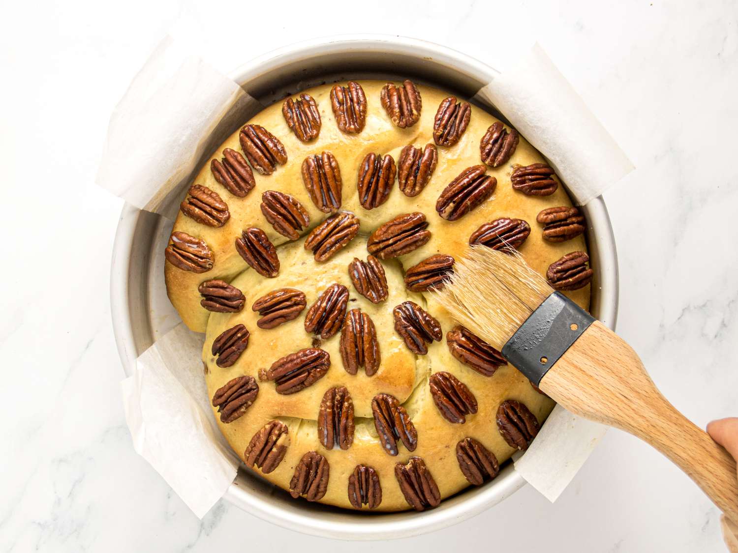 Brushing cake with melted butter in pan 