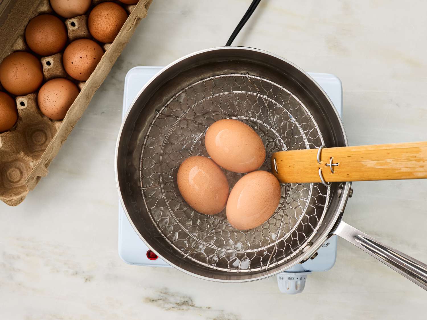 Eggs simmering in a pot on a portable stovetop
