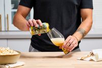 A person pouring beer into an IPA glass.