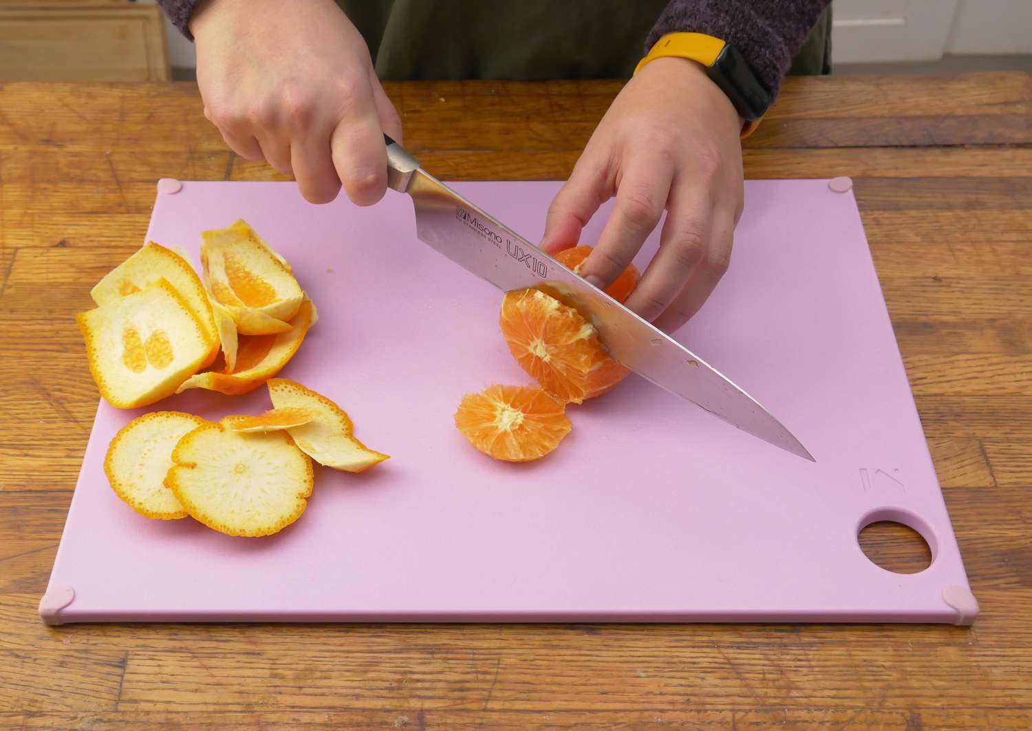 A person cutting up an orange on the reboard