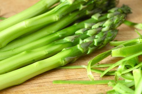 Peeled asparagus stalks on a cutting board.