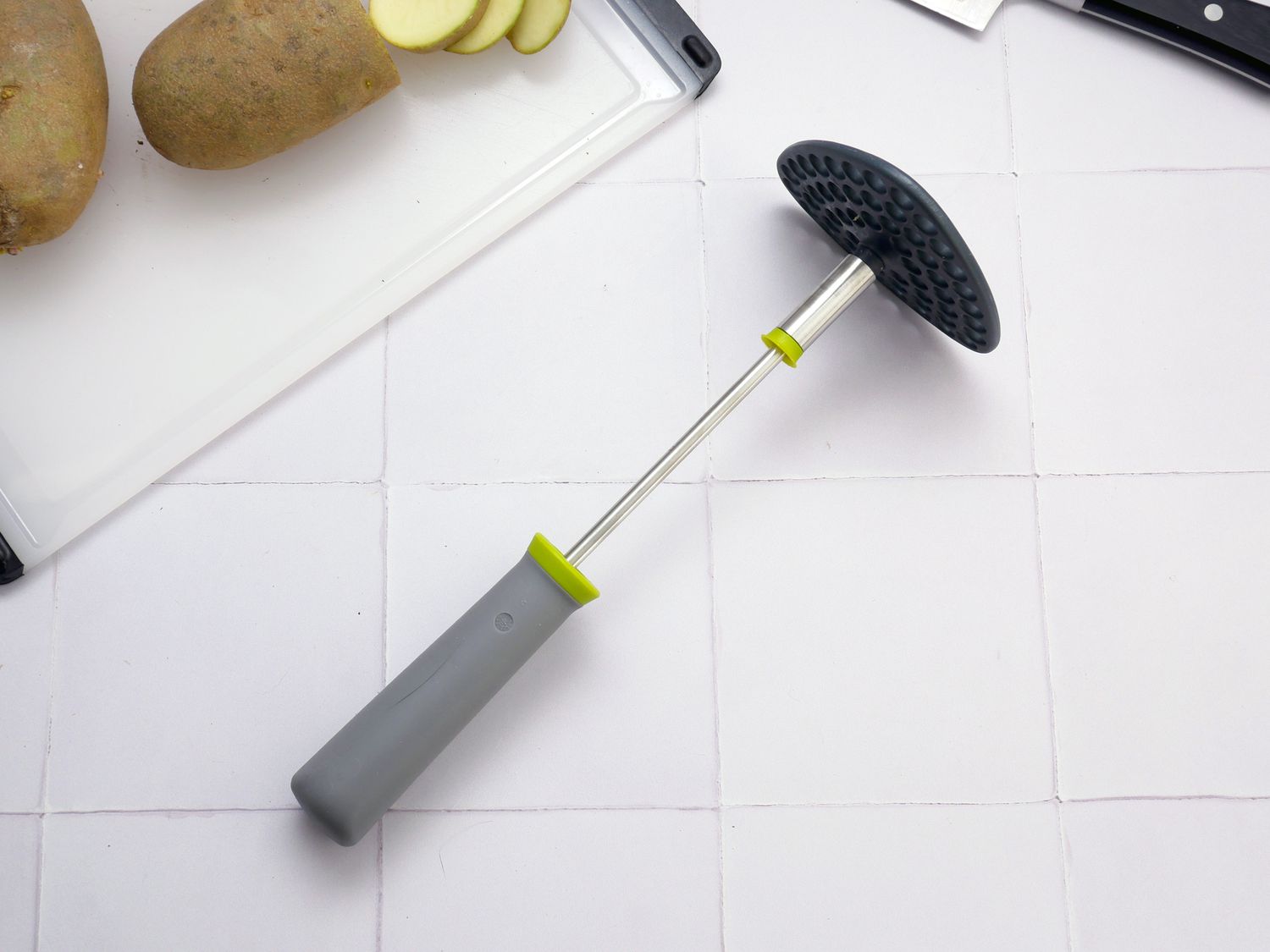 joseph joseph potato masher on a white tile surface