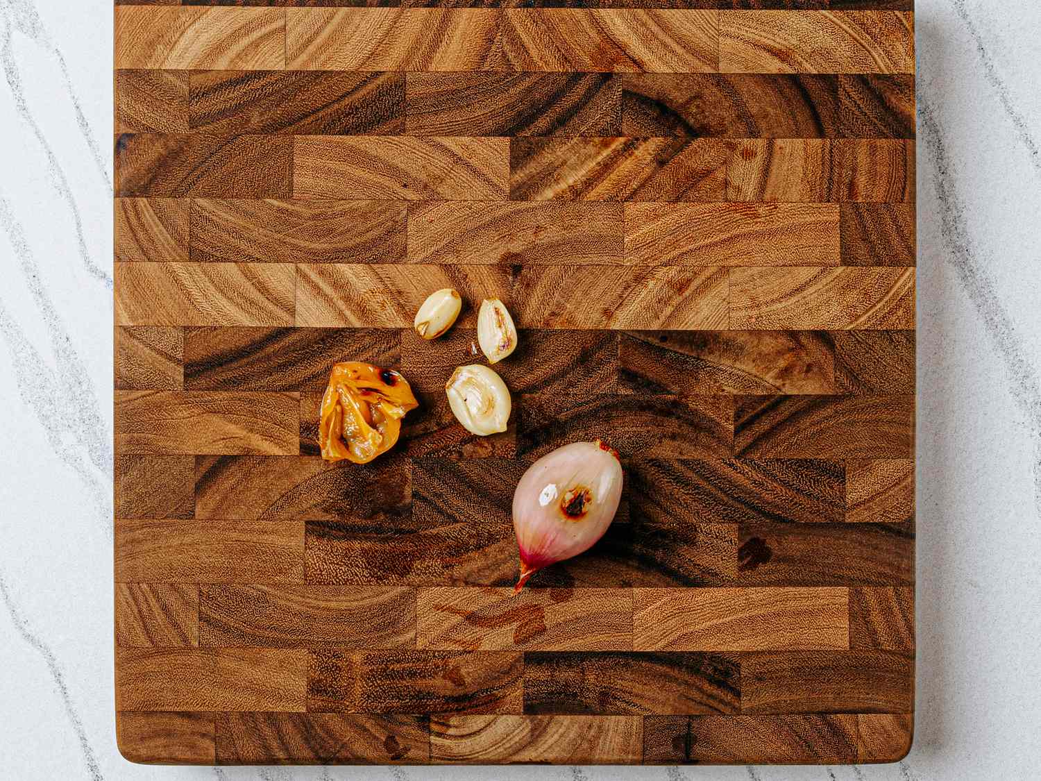Chopped cloves and a shallot on a wooden cutting board