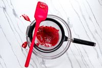 KitchenAid Classic Strainer with a red spatula and red liquid in a mixing bowl on a white surface