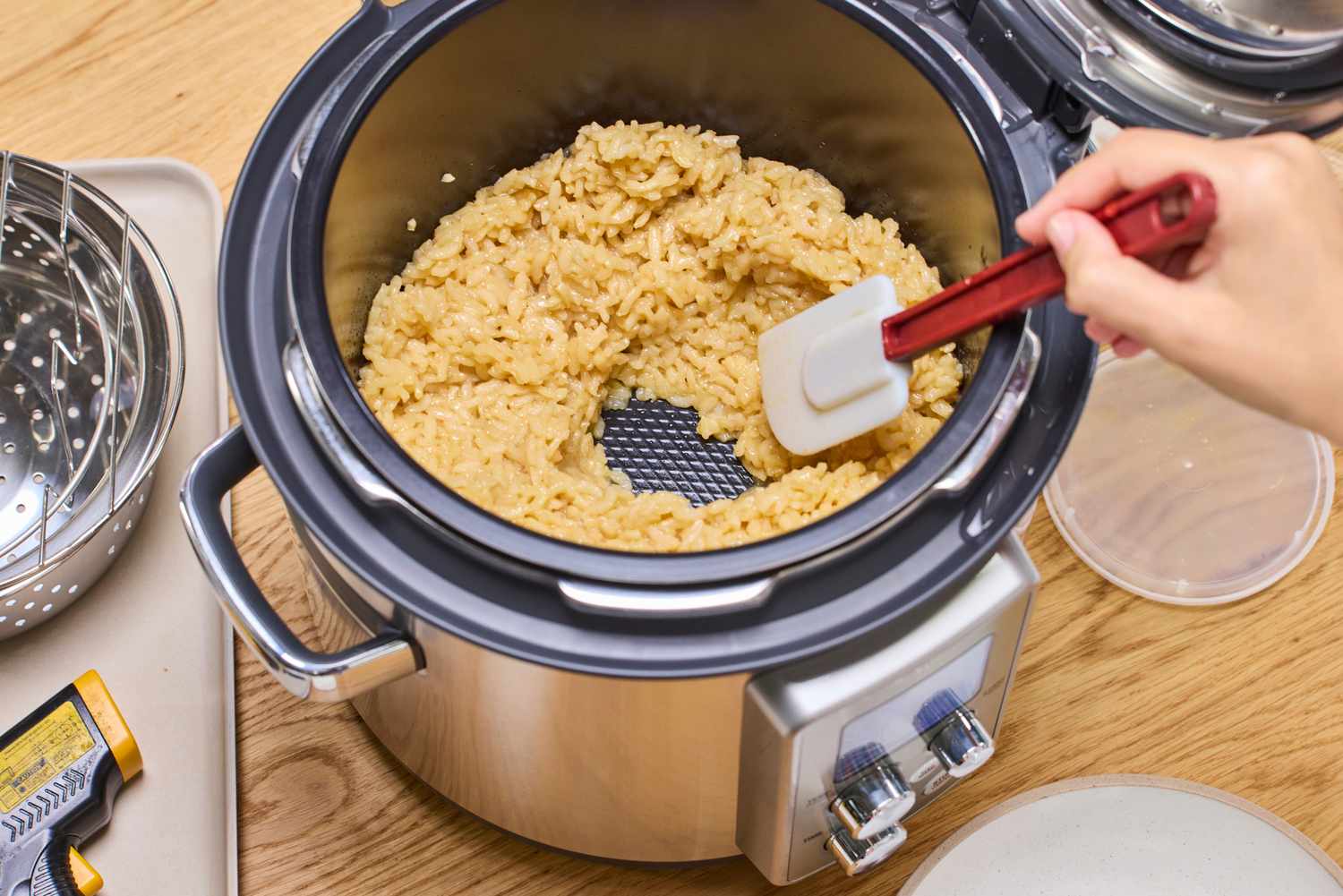 A person stirs rice cooked in the Breville the Fast Slow Pro