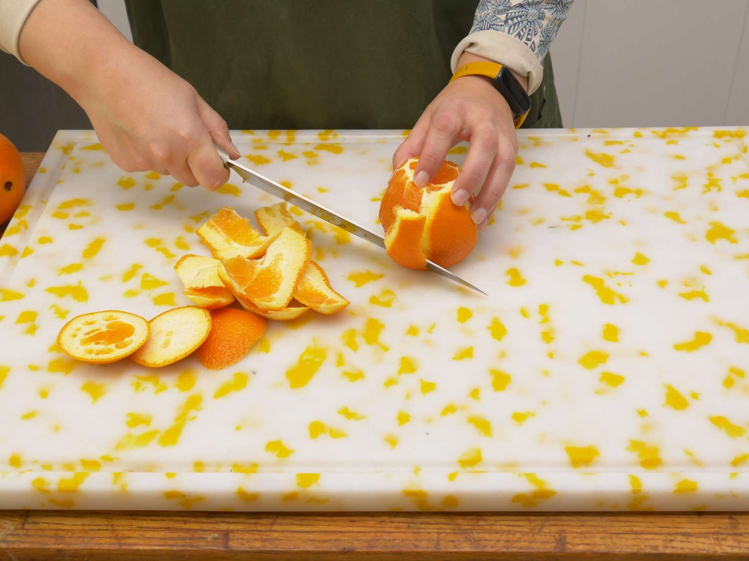 a person supreming an orange on the frederick and mae cutting board