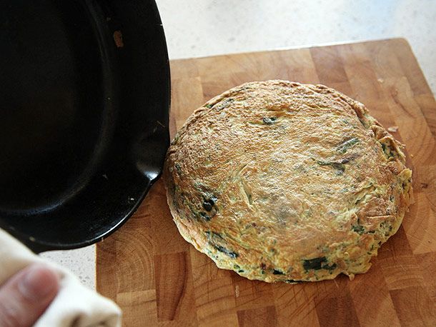 The frittata is flipped out of the pan and onto a cutting board.