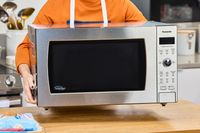 A person lifting the Panasonic Oven with Cyclonic Wave Inverter Technology