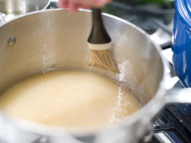 A moistened pastry brush is used to push sugar crystals down the sides of the pan.
