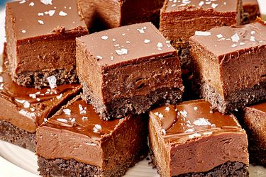 A plate with chocolate squares having a fudgy texture and a sprinkling of sea salt on top