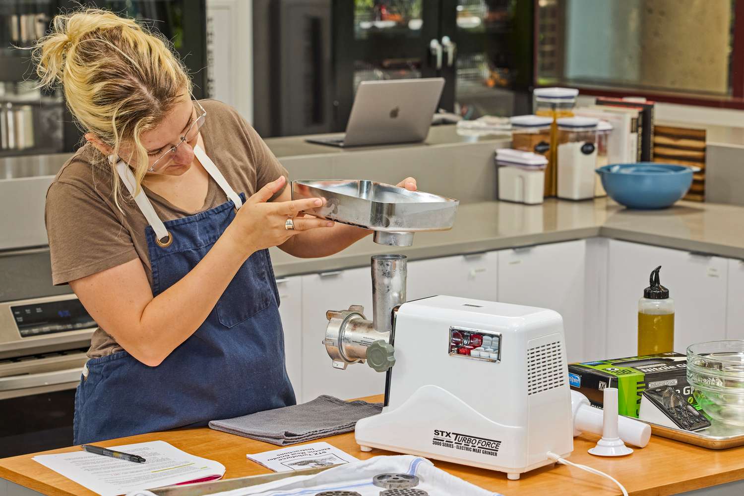 Person fixing food tray of STX International Turboforce Classic 3000 Series Electric Meat Grinder & Sausage Stuffer