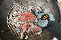 A person holds a pair of tongs while wearing the Blackstone Griddle Gloves