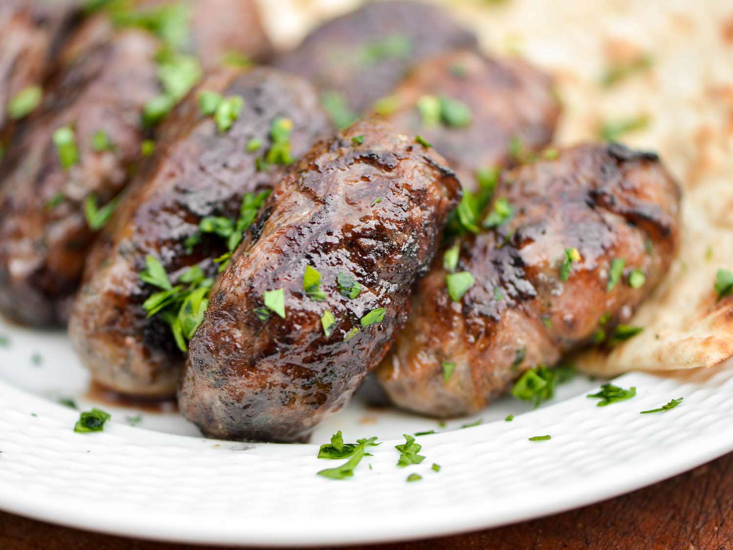 Close-up of the grilled sheftalia, garnished with minced parsley.