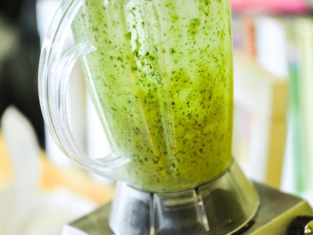 Blending bright green cilantro marinade in a blender.