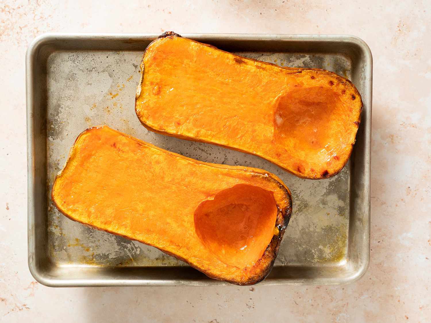 Roasted and caramelized butternut squash halves on a baking sheet.