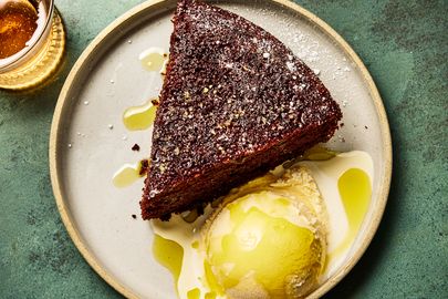 A slice of chocolate olive oil cake served with a scoop of ice cream on a plate