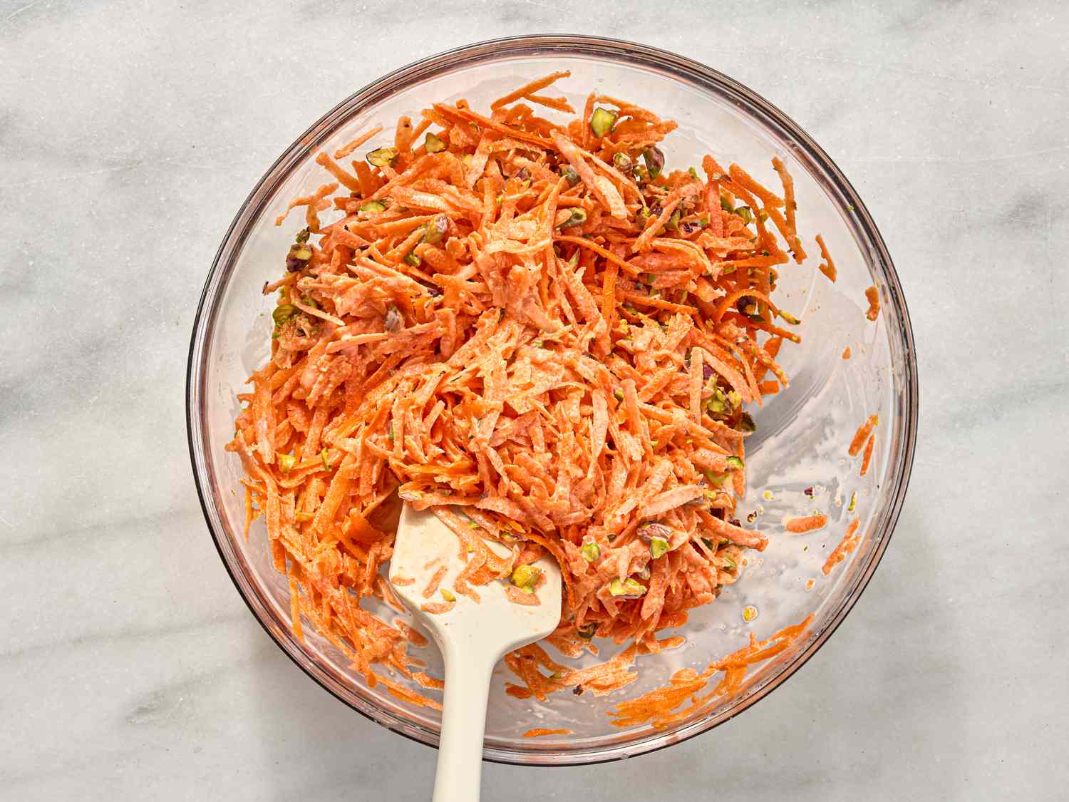 sitrring carrot mixture in bowl on a white surface 