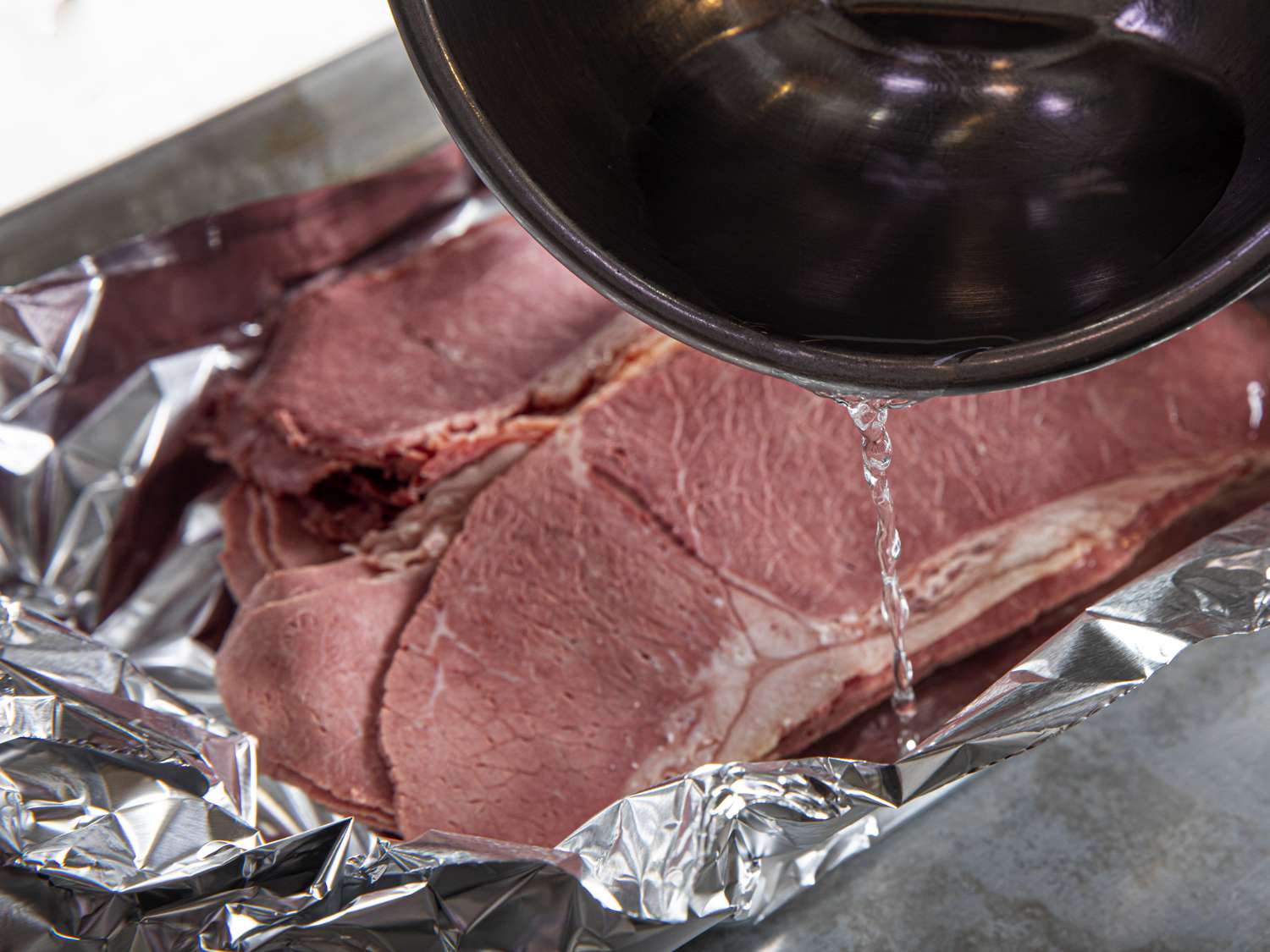 Water being added to corned beef in aluminum foil 