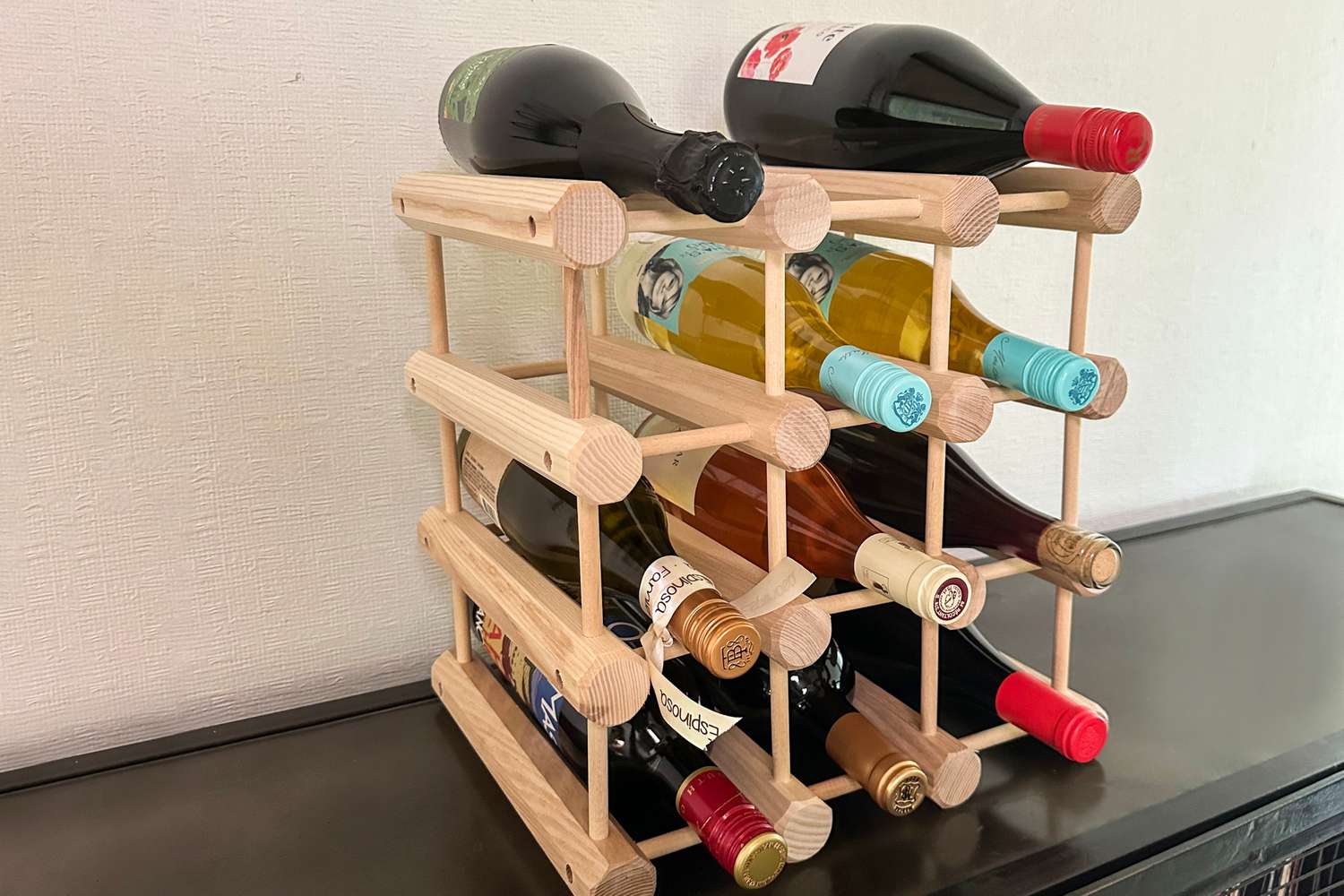 The J.K. Adams 12-bottle wine rack filled with bottles of red, white, and rosé wine.