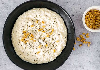 Labaniyeh bil Ruz in a black bowl with toasted pine nuts