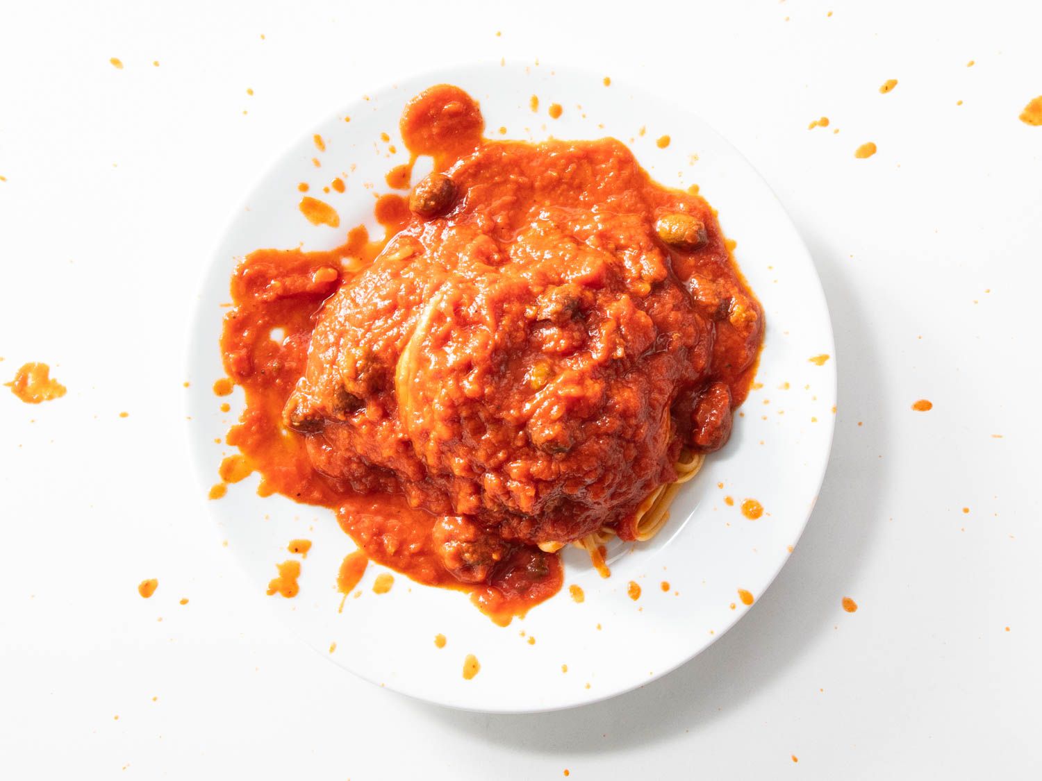Tomato sauce is splattered on a plate of spaghetti, but there's so much sauce you can't see the spaghetti underneath