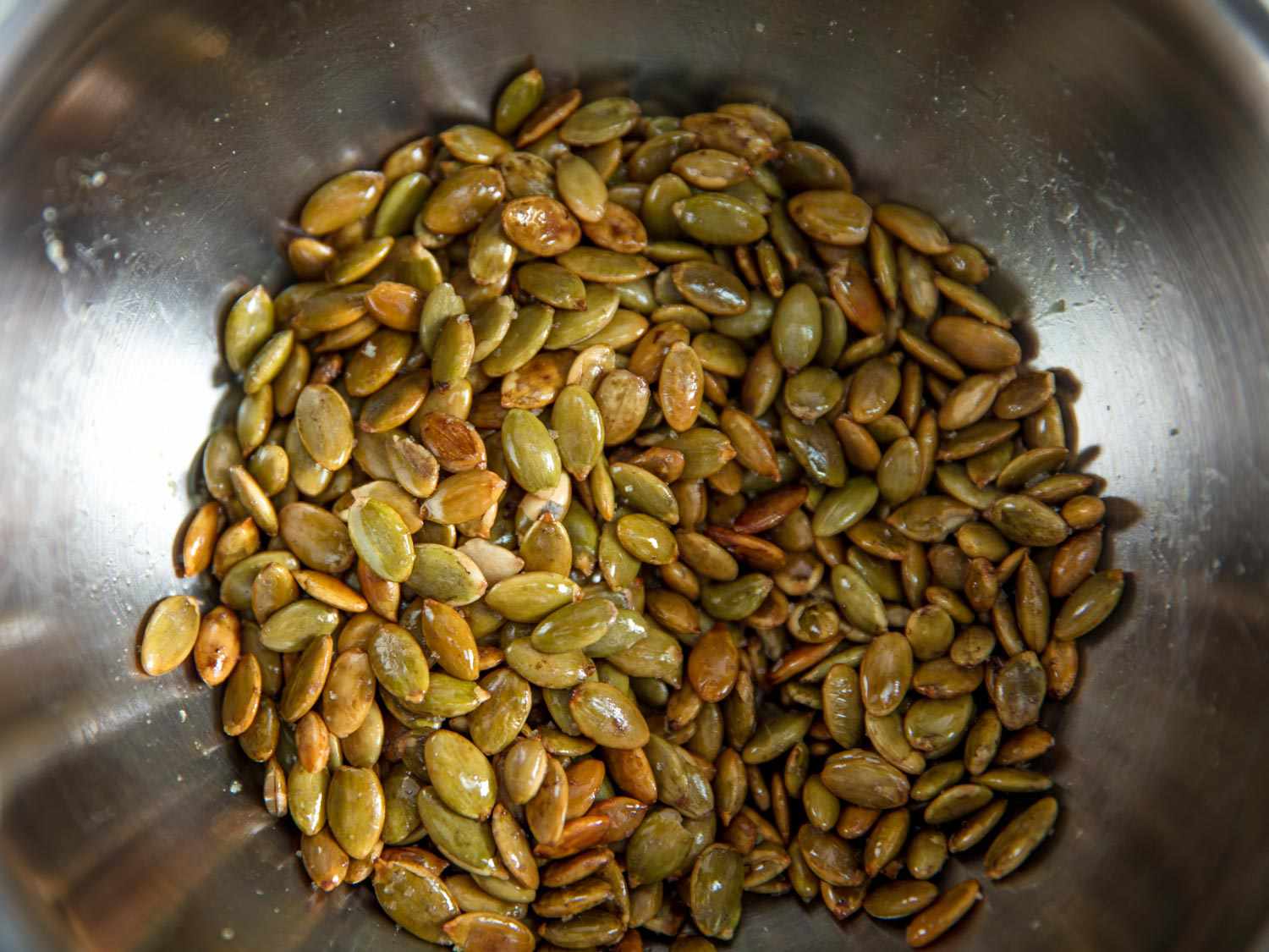 A bowl of toasted, salted, and oiled pumpkin seeds for adding to homemade granola.