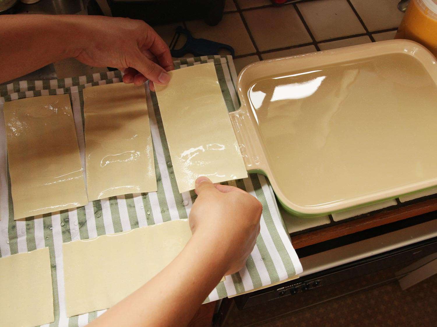 Transferring lasagna noodles to dish towels to blot excess moisture.