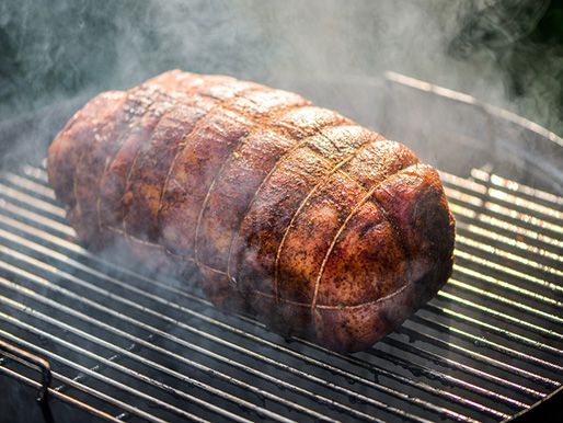 The lamb shoulder resting on a grill grate after smoking for several hours.