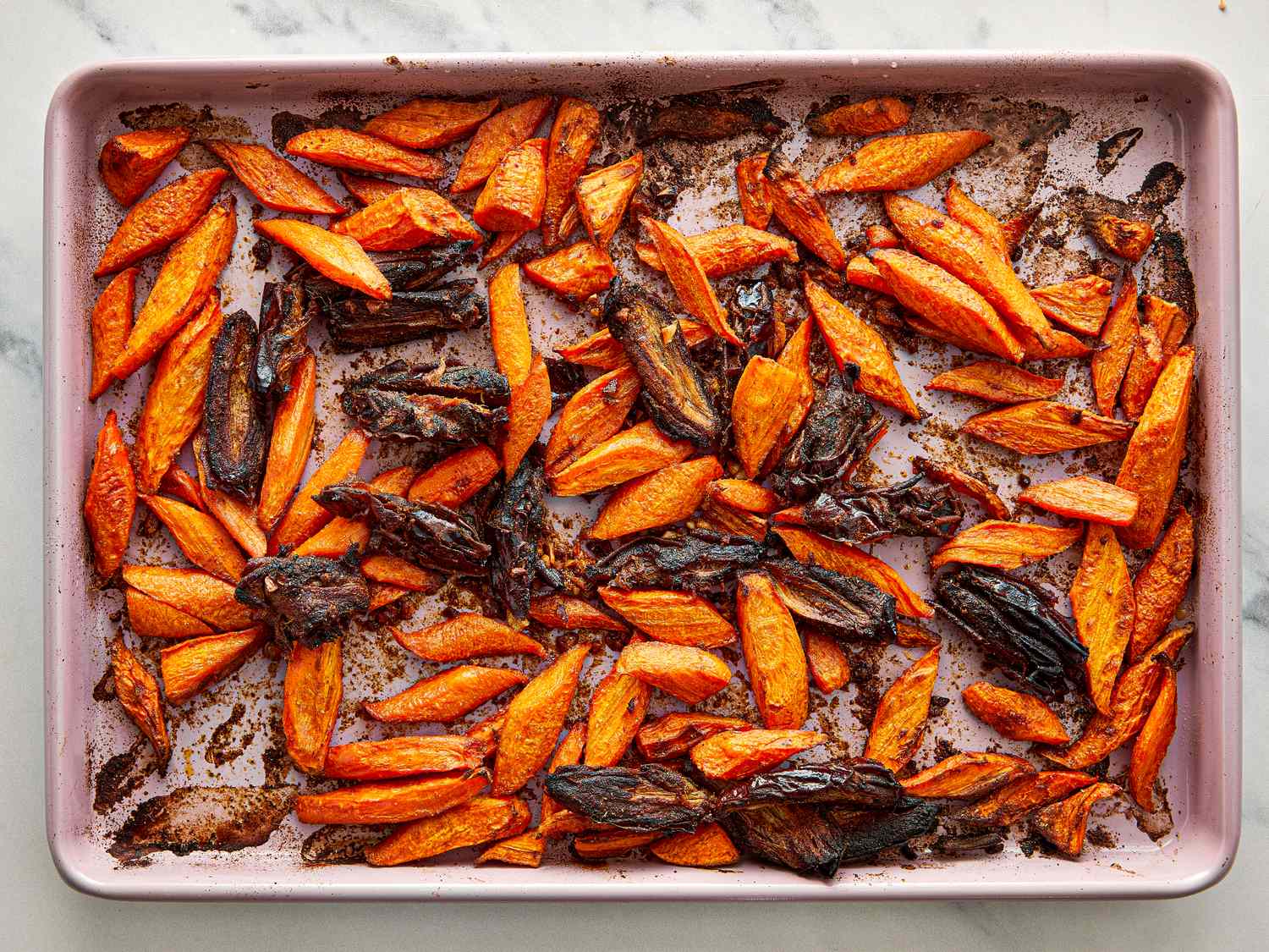Roasted carrot and date salad on a baking sheet shown after roasting