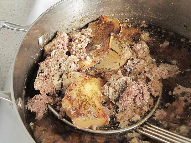 Scooping up "raft" out of pho broth with wire mesh strainer